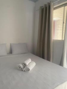 a white bed with two rolled up towels on it at ElRancho Suites in Itaparica Town