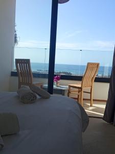 a bedroom with a bed and two chairs on a balcony at Appartement Les Vagues Vue sur Mer pour familles in Oualidia +40 photos