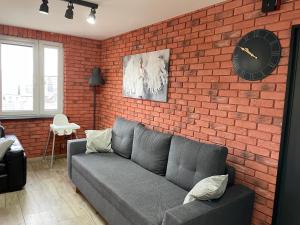 a living room with a couch and a brick wall at Apartament w centrum in Rymanów-Zdrój