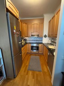 a kitchen with wooden cabinets and a stainless steel refrigerator at Charming one-bedroom apartment in Grand House in the city center of Kokkola in Kokkola