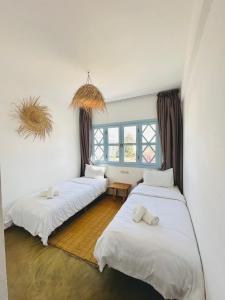 um quarto com três camas e uma janela em Appartement Les Vagues Vue sur Mer pour familles em Oualidia