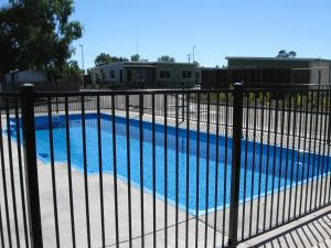a pool with a fence and a blue fence at Dooleys Tavern and Motel Capella in Capella