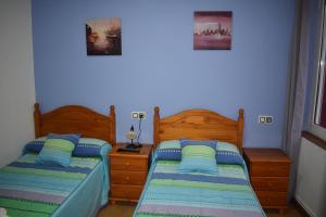2 Betten in einem Schlafzimmer mit blauen Wänden in der Unterkunft Pensión 15 de Mayo in La Pola de Gordón