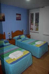 zwei Betten in einem Zimmer mit blauen Wänden in der Unterkunft Pensión 15 de Mayo in La Pola de Gordón