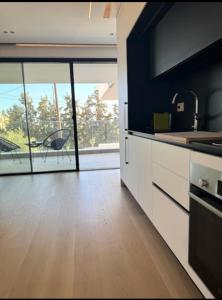 Una cocina con gabinetes blancos y una ventana grande. en LuxApart74 l Comfy & Minimal Stay in Ierapetra, en Ierápetra