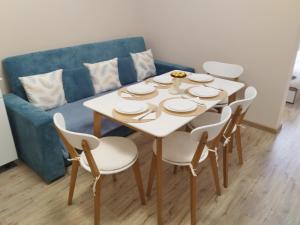 einen weißen Tisch mit Stühlen und eine blaue Couch in der Unterkunft Apartment Bee Happy, Pchelinski Bani in Pchelin