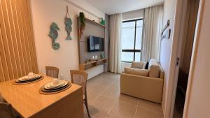 a living room with a dining table and a couch at Flat 1 quarto Beach Porto - By Duuna Temporada in Porto De Galinhas