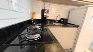 a kitchen with a stove with two pans on it at Flat 1 quarto Beach Porto - By Duuna Temporada in Porto De Galinhas +24 photos