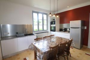 a kitchen with a table with chairs and a refrigerator at L'Oustal de Salers in Salers