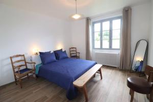 a bedroom with a blue bed and a chair at L'Oustal de Salers in Salers
