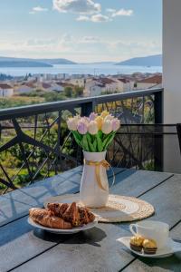 een tafel met een vaas met bloemen en een bord met eten bij Apartmani Zaja in Trogir