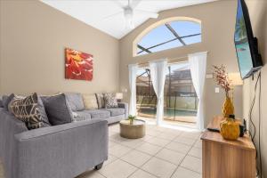 een woonkamer met een bank en een tv bij Summer Getaway - 5-Bedroom Home with Private Pool! in Kissimmee