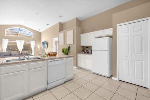 een keuken met witte kasten en een witte koelkast bij Summer Getaway - 5-Bedroom Home with Private Pool! in Kissimmee +31 foto's