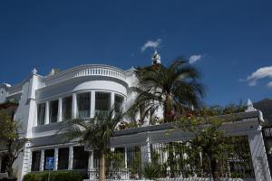 a white house with a palm tree in front of it at Hotel Boutique Cultura Manor by Brater in Quito