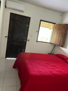 a bedroom with a red bed and a window at Pousada Metropolitana Salvador in Candeias