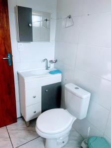 a bathroom with a white toilet and a sink at Bombinhas, Casa mobiliada 1 quarto in Bombinhas