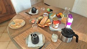 a table with a breakfast of bread and food on it at Halte détente chez Sylvie près A71 Bourges - chambres avec sauna, billard, salle ciné in Civray
