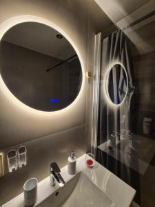 a bathroom with a sink and a round mirror at Apartmán LUX Lučenec in Lučenec