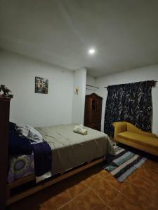 Un dormitorio con una cama y una silla amarilla. en Abuelita, en Santa María Tonantzintla