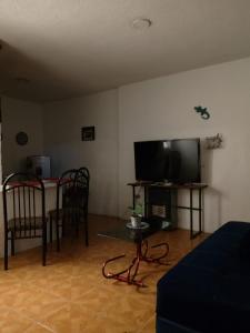 Una sala de estar con televisión, mesa y sillas. en Abuelita, en Santa María Tonantzintla
