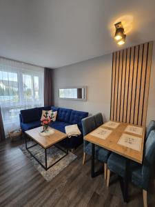 a living room with a blue couch and tables at Apartament KOJA in Rewal