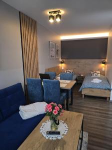 a living room with blue couches and a table with flowers at Apartament KOJA in Rewal