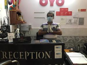 a man wearing a face mask while standing behind a counter at Hotel O Plus One Hotel Residency in New Delhi