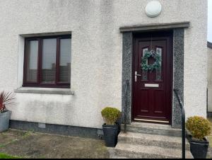 a house with a red door and two windows at 60 Springfield Road in Stornoway +3 photos
