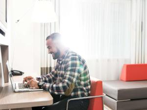 a man sitting at a desk using a laptop computer at Novotel Brussels City Centre in Brussels