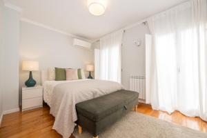 a white bedroom with a bed and a chair at Casa Alecrim in Tavira