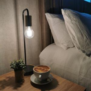 a cup of coffee on a table next to a bed at Rooms at the Village in Omagh +9 photos