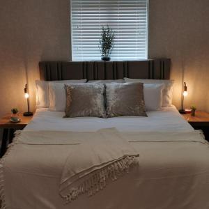 a large white bed with pillows and a window at Rooms at the Village in Omagh