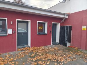 a red house with leaves on the ground in front of it at Lunaria Living I Studio - Ambilight 55 Zoll TV - Retro-Konsole -Parkplatz - Zentral - HBF-nah & VW-Tor 17 in Wolfsburg