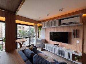 Una sala de estar con un sofá azul y un televisor de pantalla plana. en ID Vida Urbana - Equilíbrio perfeito entre praticidade, conforto e localização privilegiada - Setor Oeste, en Goiânia