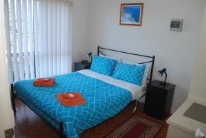 a bedroom with a blue bed with two towels on it at Lookout Holiday Units in Lakes Entrance