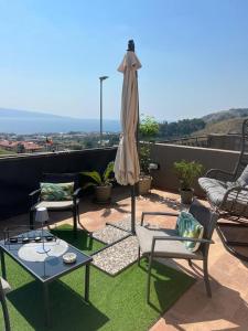eine Terrasse mit Stühlen, einem Tisch und einem Sonnenschirm in der Unterkunft Gardenie Home: delizioso villino vista mare in Messina