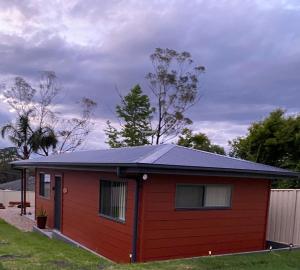 ein rotes winziges Haus mit schwarzem Dach in der Unterkunft Ella Cottage - Relaxing romantic escape-Southern Highlands 