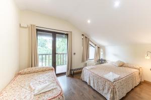 Un dormitorio con dos camas y una ventana en El Herrén Del Abuelo, en Vegas de Matute