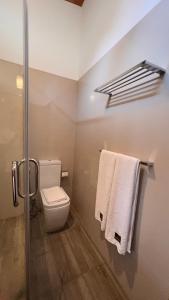 a bathroom with a toilet and towels on a rack at Avanee Hotel in Mawanella
