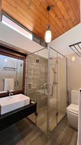 a bathroom with a glass shower and a sink at Avanee Hotel in Mawanella