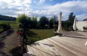 eine Holzterrasse mit Sonnenschirmen im Garten in der Unterkunft Chambre de 15m2 à la campagne avec salle de bains in Vacqueville