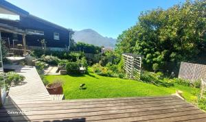 Un patio trasero con terraza de madera y un patio con césped. en Puka Mala Tiny House, en Ciudad del Cabo