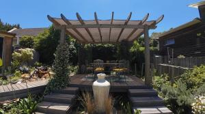 una terraza de madera con pérgola en un jardín en Puka Mala Tiny House, en Ciudad del Cabo 5 fotos más
