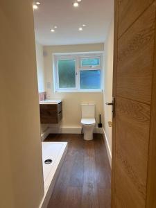a bathroom with a toilet and a sink and a window at LivinSpace- Modern and spacious 2 bed flat in Central Sutton in Sutton