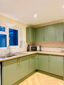 a kitchen with green cabinets and a microwave at LivinSpace- Modern and spacious 2 bed flat in Central Sutton in Sutton +5 photos