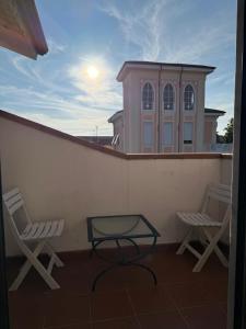 two chairs and a table on a balcony with a building at Joe's apartments in Carrara