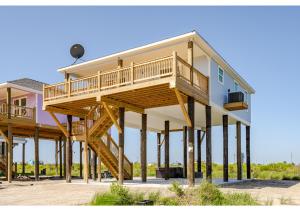 ein großes Haus mit Holztreppe, die hinauf führt in der Unterkunft Blue Lagoon with Hot Tub and Golf Cart! in Bolivar Peninsula