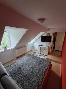 a attic living room with a couch and a rug at KissApartman in Kőszeg