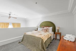 a white bedroom with a bed with a green headboard at Character Central in Christchurch +26 photos