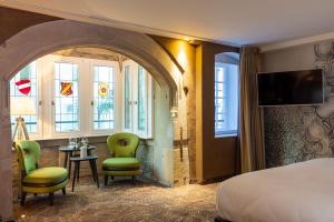 Habitación de hotel con cama, sillas y ventanas en Hotel Restaurant L'Orchidee, en Ensisheim